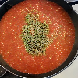 a tomato sauce that has been heated for 2 minutes and then had dried basil, oregano, and garlic added to it. the sauce has then been cooked for an additional 5 minutes.