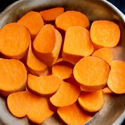 a metal dish is coated with cooking spray and then layered with sliced sweet potatoes.